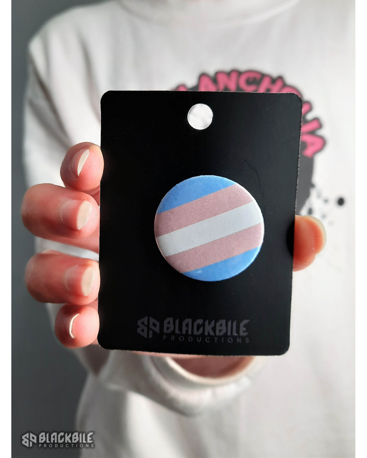 A small button badge in the colours of the trans flag.