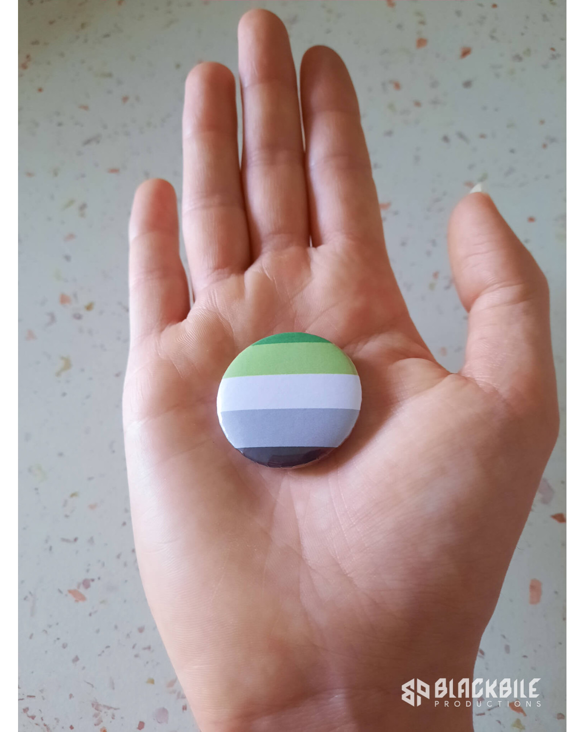 A small button badge in the colours of the aromantic flag.